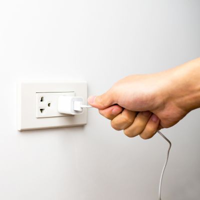 Person unplugging electric charger from wall outlet